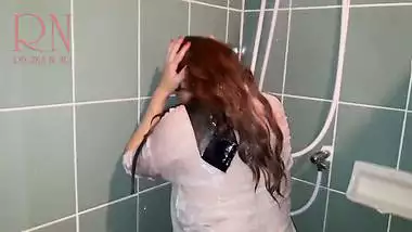 A chick in clothes under the shower. Wet...